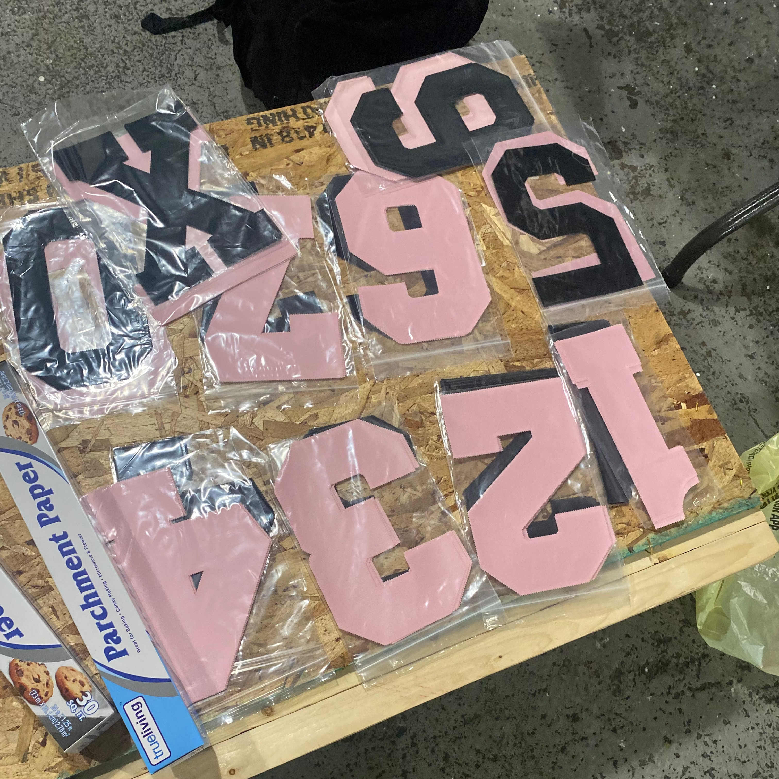 Pink and black lettering on a wooden board with parchment paper in the background.